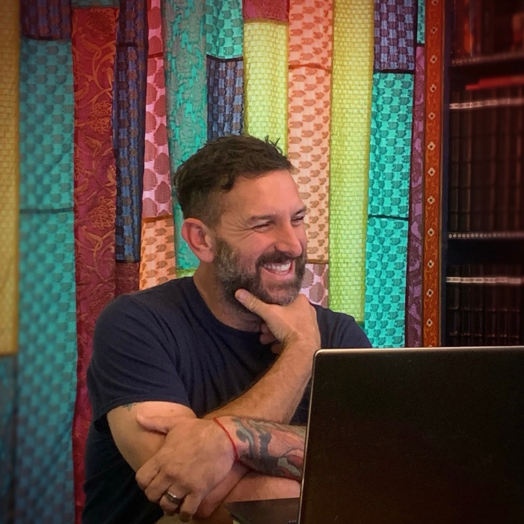 Franz Manfredi smiling at a laptop.